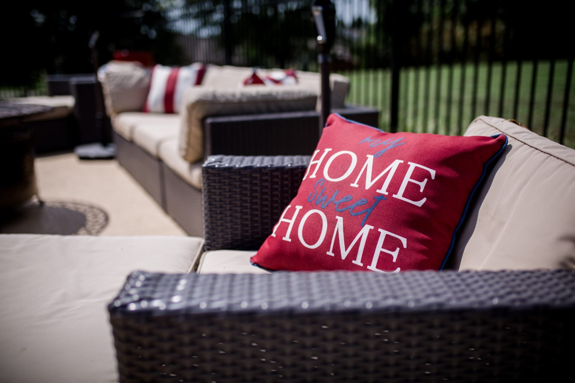Outdoor patio furniture with home sweet home pillow pop of red color.